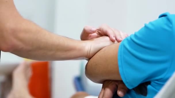Gehakte onherkenbare man knijpen en wrijven elleboog van gewas patiënt tijdens hersteltherapie in kliniek - Video