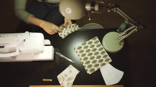 неузнаваемая ремесленница, использующая современную швейную машинку при создании мягких образцов ткани с творческим зеленым узором возле лампы в мастерской в чердачном стиле - Кадры, видео