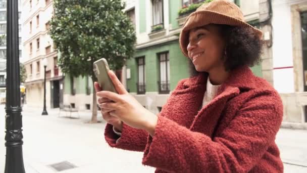 Sisältö Afrikkalainen amerikkalainen nainen seisoo kaupungissa ja ottaa omakuvan älypuhelimella - Materiaali, video