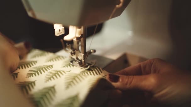 nerozpoznatelná řemeslnice používající moderní šicí stroj při vytváření měkkých textilních vzorků s kreativním zeleným vzorem v blízkosti lampy v dílně ve stylu podkroví - Záběry, video