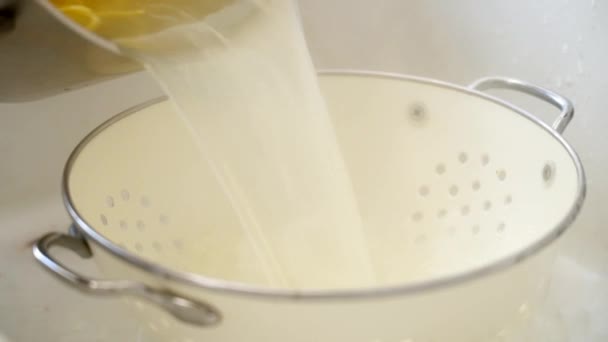 Sluiten van gewas anonieme mannelijke morsen hete gekookte spaghetti uit pan in vergiet tijdens het bereiden van pasta in de keuken - Video