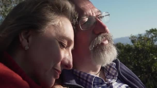 Close-up zijaanzicht van rustige laatstejaars paar knuffelen en slapen terwijl ze samen rusten in de natuur in de zonnige dag - Video