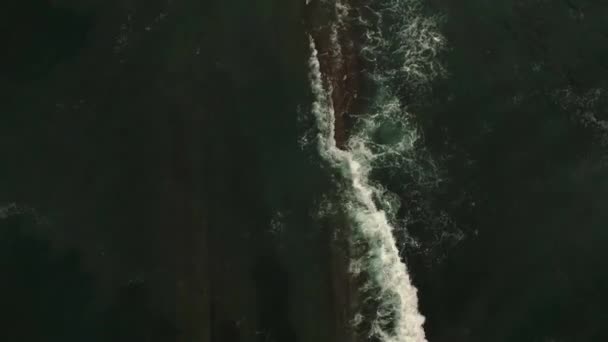 Breathtaking aerial view of powerful ocean with foamy waves crashing over rough rocky cliffs - Materiał filmowy, wideo