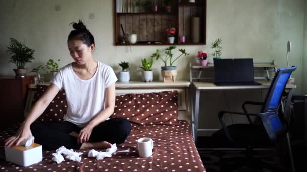 Нахмурилась этническая женщина в домашней одежде, сидя на кровати с бегающим носом во время простуды - Кадры, видео