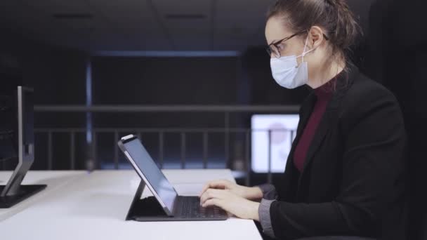 Πλευρική άποψη της επιχειρηματία ειδικός κάθεται στο τραπέζι και πληκτρολογώντας στο πληκτρολόγιο στο tablet με άδεια λευκή οθόνη, ενώ εργάζονται στο χώρο εργασίας - Πλάνα, βίντεο