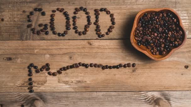 "Top view stop motion animación de granos de café frescos asados en taza roja formando inscripciones buenos días y café en mesa de madera - Imágenes, Vídeo