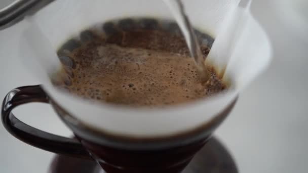 Fentről közelkép folyamat öntsük forró víz a papír szűrő friss őrölt kávé előkészítése során aromás forró ital - Felvétel, videó