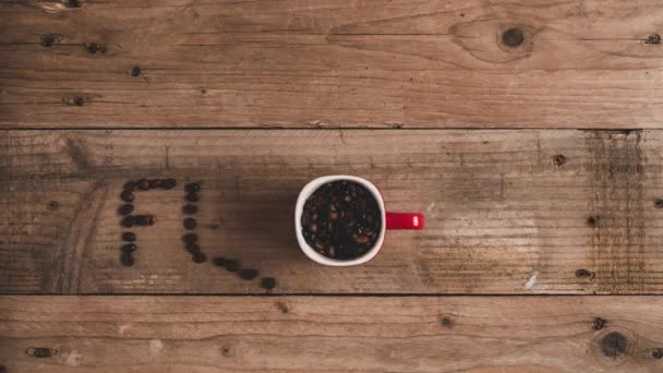 上ビューストップモーションアニメーションのロースト新鮮なコーヒー豆で赤マグカップ形成碑文フラップ上の木製テーブル - 映像、動画