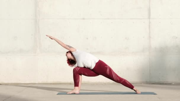 Mujer haciendo guerrero dos yoga en extendido triángulo pose en calle - Metraje, vídeo