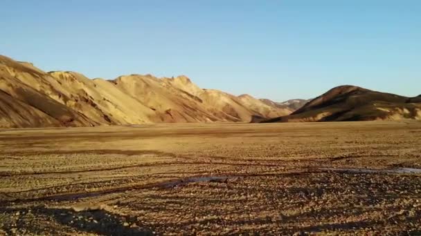 Aufnahme eines riesigen Tals mit trockenem Gras und vielen schmalen, geschwungenen Flüssen in der Nähe rauer, verlassener Hügel vor blauem Himmel in Island - Filmmaterial, Video