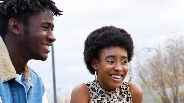 Kıvırcık saçlı, modaya uygun kot giysiler giyen modern Afro-Amerikan çift şehrin sokaklarında yan yana dururken gülüyor ve başka tarafa bakıyor. - Video, Çekim
