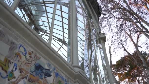 Castillo antiguo geométrico con ventanas de cristal que reflejan árboles, Palacio de Cristal, Parque del Retiro, Madrid, España - Metraje, vídeo
