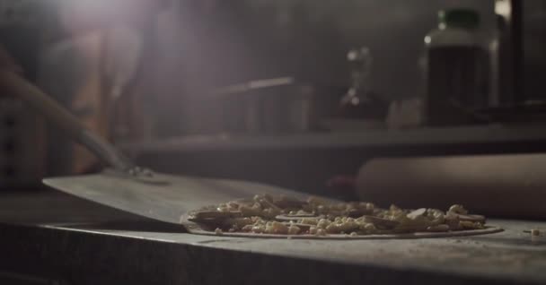 Cultivado irreconocible chef masculino tomando pizzas con cáscara y poniendo en horno caliente mientras trabaja en la cocina de la cafetería - Metraje, vídeo