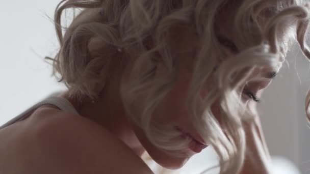 Seitenansicht der Frau mit Eisen-Curling-Haar zu Hause, während sie stilvolle Frisur - Filmmaterial, Video