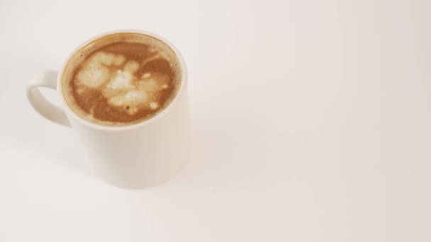 Z góry krople ciepłego mleka wpadające do białego ceramicznego kubka świeżo warzonego aromatycznego cappuccino - Materiał filmowy, wideo