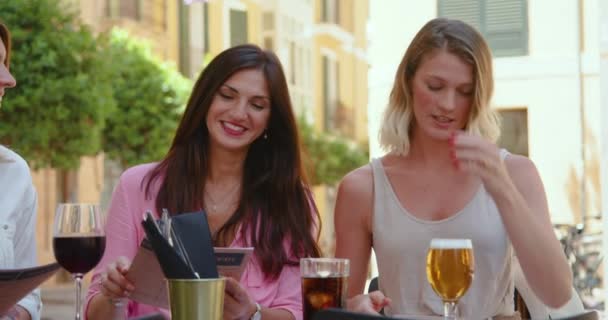 Csoportja trendi gyönyörű felnőtt nők nevetnek hangosan, miközben megosztják finom rágcsálnivalók alkoholos italok járda kávézó - Felvétel, videó