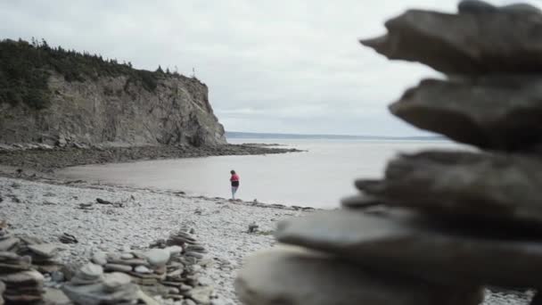 Back view of anonymous female tourist  walking along rocky sea during vacation in Peggys Cove, Canada - Footage, Video