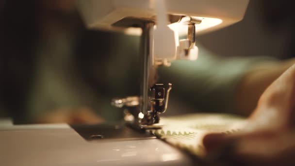 unkenntliche Handwerkerin mit moderner Nähmaschine beim Erstellen weicher Stoffmuster mit kreativem grünen Muster in der Nähe von Lampen im Loft-Stil - Filmmaterial, Video