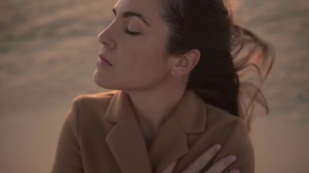 Soñadora helada mujer pensativa en abrigo de pie en la playa en el día ventoso en Levante - Imágenes, Vídeo