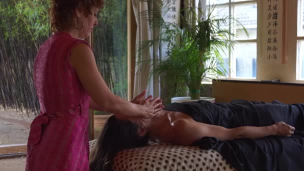 Боковой вид расслабленной женщины, наслаждающейся альтернативной аюрведической Марма-терапией во время массажа в спа-салоне - Кадры, видео