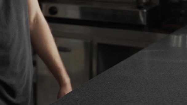 Pan vista a destra di uomo anonimo spolverare tavolo in metallo con pavimento prima di cucinare in cucina moderna nel ristorante - Filmati, video