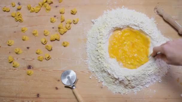 Vista dall'alto del raccolto anonimo cuoca impastatrice con cucchiaio mentre prepara gustosi tortellini italiani a casa - Filmati, video