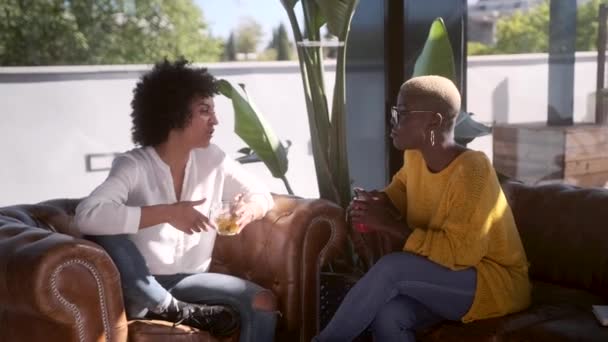 Mutlu Afro-Amerikan kadın arkadaşlar terasta oturup şakalara gülerken ve birbirlerine bakarken konuşuyorlar. - Video, Çekim