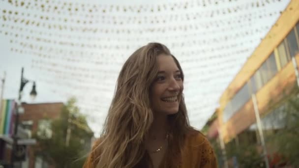 Blick von unten auf eine glückliche Frau, die eine mit Girlanden geschmückte Straße in Montreal hinuntergeht - Filmmaterial, Video