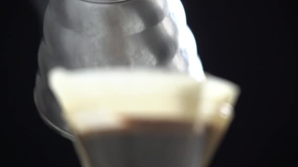 Processo di primo piano di versare acqua calda nel filtro di carta con caffè macinato fresco durante la preparazione di bevande calde aromatiche - Filmati, video