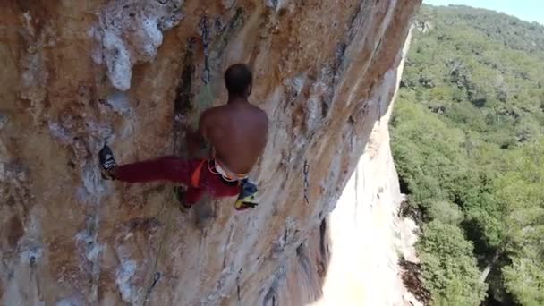 Von oben der starke, bartlose Bergsteiger, der an sonnigen Tagen den felsigen Hang des Berges erklimmt - Filmmaterial, Video
