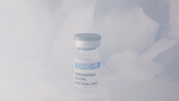 冷凍庫に氷の上に置かれたCOVID 19からのワクチンでガラス瓶の閉鎖 - 映像、動画
