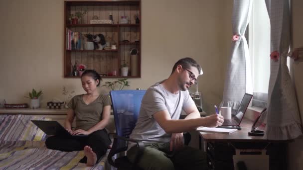 Couple occupé d'entrepreneurs en tenue décontractée assis dans la chambre et travaillant en ligne tout en naviguant sur l'ordinateur - Séquence, vidéo