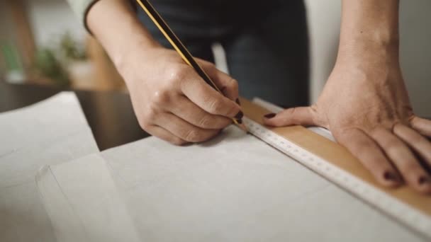 Неузнаваемая швея, стоящая, наклонившись вперед, за столом с ножницами и бумагой в студии в стиле лофт - Кадры, видео