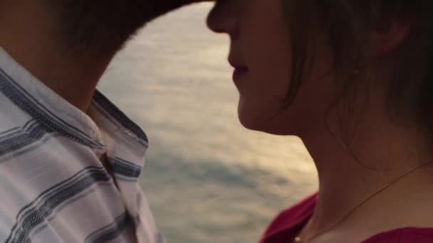 Recortado irreconocible pareja romántica besándose mientras que de pie en el borde de áspero acantilado rocoso contra el mar al atardecer - Metraje, vídeo