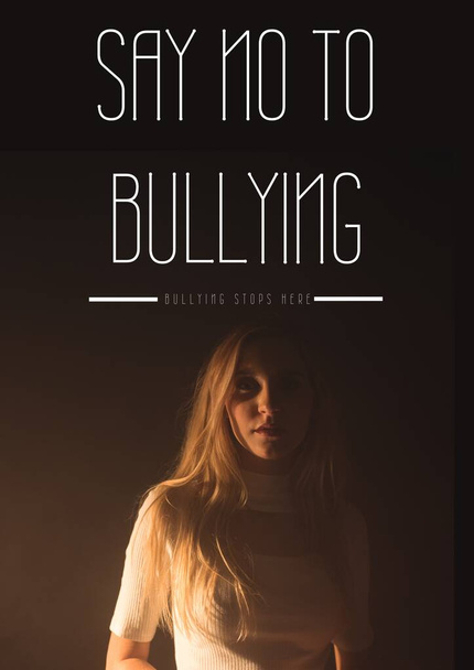 Digitally generated image of say no to bullying text over woman against black background. combating bullying concept - Photo, image