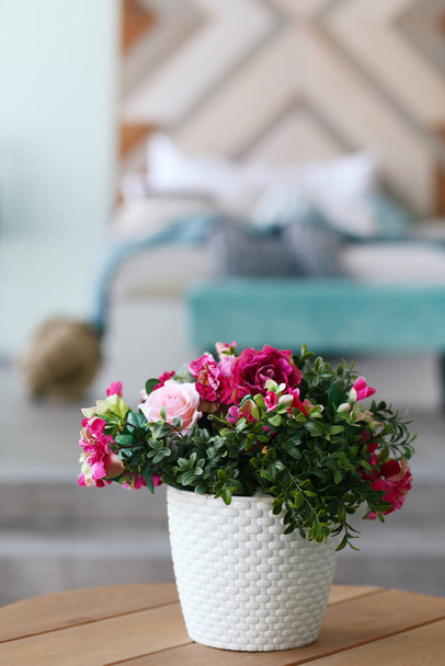 modern bedroom close up fragment with flowers in vase, sofa and pillows on background - Photo, Image