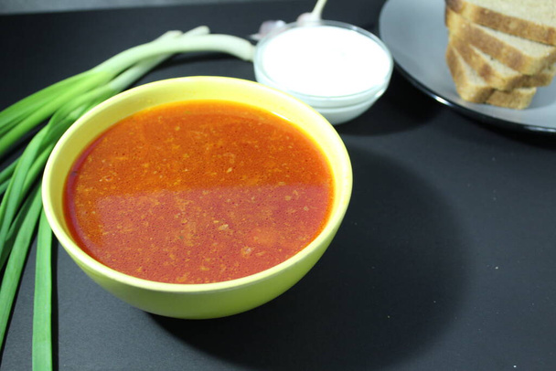 boršč červená polévka národní kuchyně se zeleným cibulovým chlebem na černém pozadí s místem pro text a copyspace. - Fotografie, Obrázek