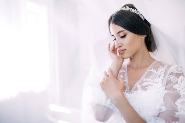tender girl bride with wedding hairstyle and makeup prepare for the ceremony. - Foto, afbeelding