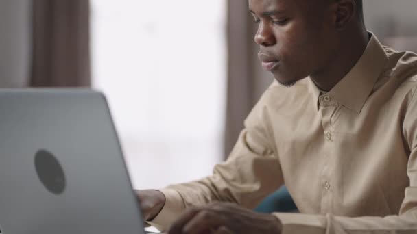 negro estudiante masculino está trabajando con el ordenador portátil, el envío de mensajes en las redes sociales o en el chat de trabajo, retrato de tiro - Metraje, vídeo