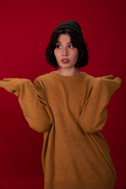 hipster menina em preto de malha boné e suéter posando com as mãos de manga comprida para cima - Foto, Imagem