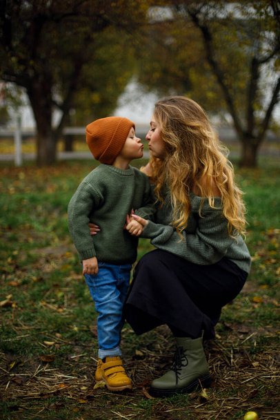 O miúdo quer beijar a mãe no jardim ou no rancho. retrato de mãe e filho. infância e maternidade. mulher e menino em um parque ou jardim em um dia nublado - Foto, Imagem