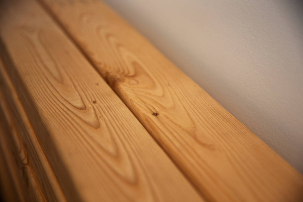 Свіжий дерев'яний промінь. Деревина укладається біля стіни. Поверхня необробленого дерев'яного бруса
 - Фото, зображення
