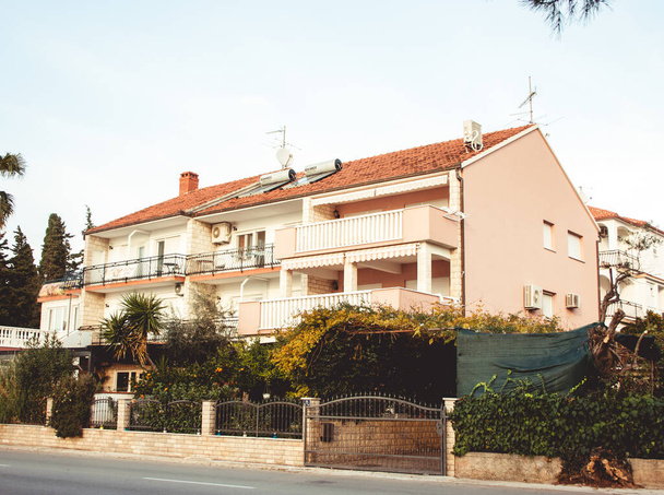 Woonhuis in Kroatië op een zonnige zomerdag met balkons en fruitbomen in de tuin. Het huis is voorzien van airconditioners. Straatzicht - Foto, afbeelding
