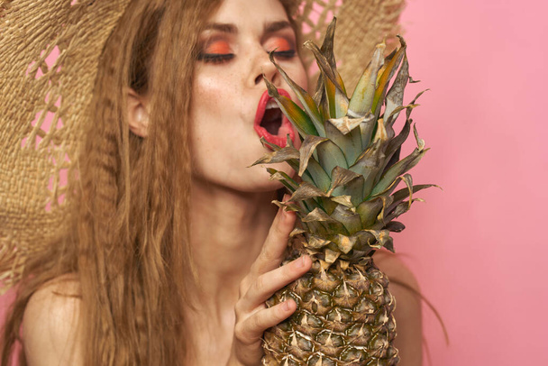 woman in beach hat pineapple exotic swimsuit pink background - Zdjęcie, obraz