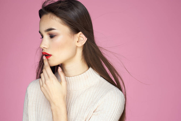 Pretty brunette in a white sweater red lips attractive look pink background - Foto, Imagen