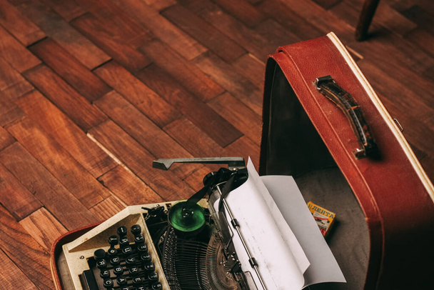 vintage schrijfmachine met wit papier staat binnen op de vloer - Foto, afbeelding