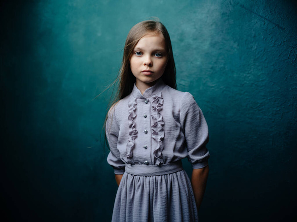 Turkuaz arka plan modeli üzerinde gri bir elbiseyle güzel bir kızın portresi. - Fotoğraf, Görsel