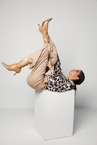 woman lying upside down fashionable clothes brown boots studio cosmetics - Foto, afbeelding