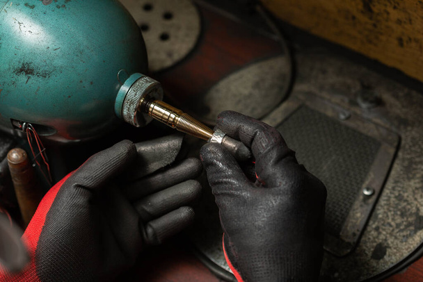человек в защитных перчатках полирует серебряное кольцо молотилкой - Фото, изображение