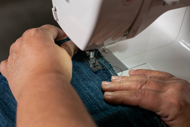 年上の女性の手の詳細ショット,彼女のミシンで縫製. - 写真・画像